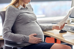 pregnant employee reading papers at office